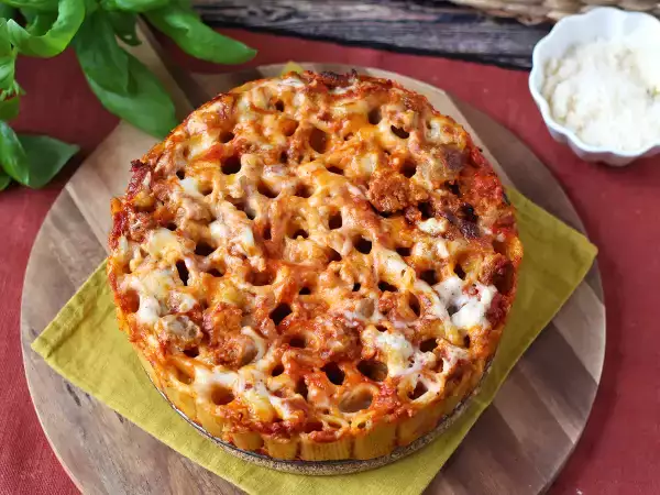 Resepti Uunissa paistettu rigatoni-timballo, jossa on makkaraa, besciamellaa ja mozzarellaa